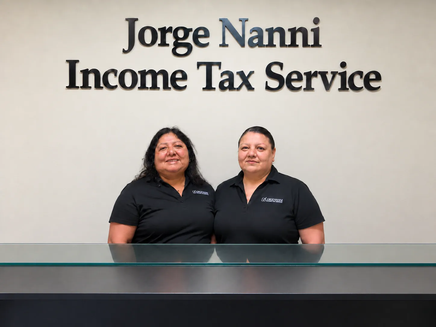 Two staff members behind the reception counter beneath the Jorge Nanni Income Tax Service sign in Santa Ana.